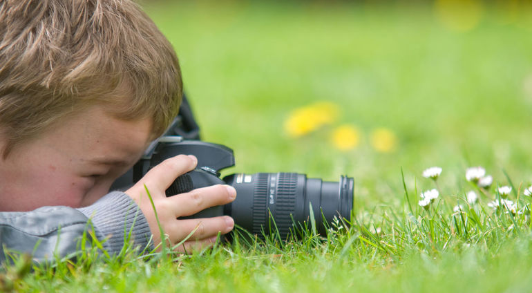 Chłopiec Fotografuje Leżąc Na Trawie