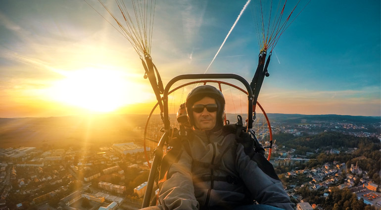 Mężczyzna latający motoparalotnią o zachodzie słońca