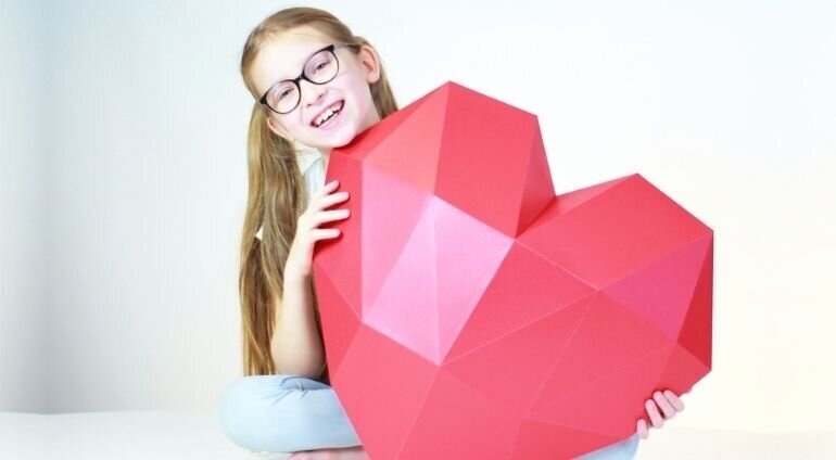 Kartonowy model serca trzymany przez dziewczynkę