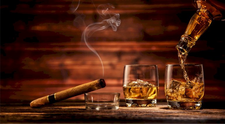 Dwie szklanki z whisky i cygaro