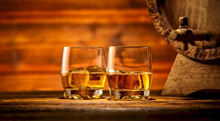 Dwie szklanki z whisky obok karafka z trunkiem