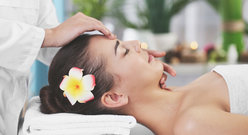 Kobieta z kwiatem we włosach podczas masażu twarzy.