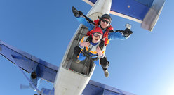 Uśmiechnięta dziewczyna wyskakuje ze spadochronem z samolotu